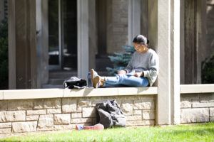 female student studying outside on ledge